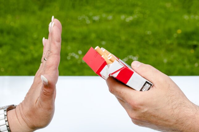 Il gesto di una mano che manifesta rifiuto per le sigarette, offerte da una altra persona